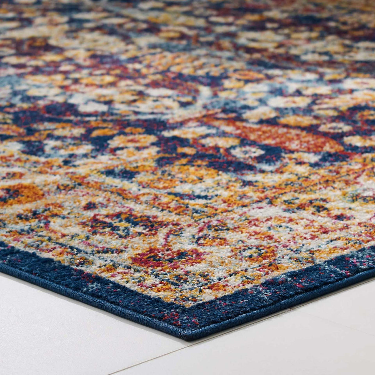 A slim, navy-bound corner gives the colorful floral border a crisp finish.