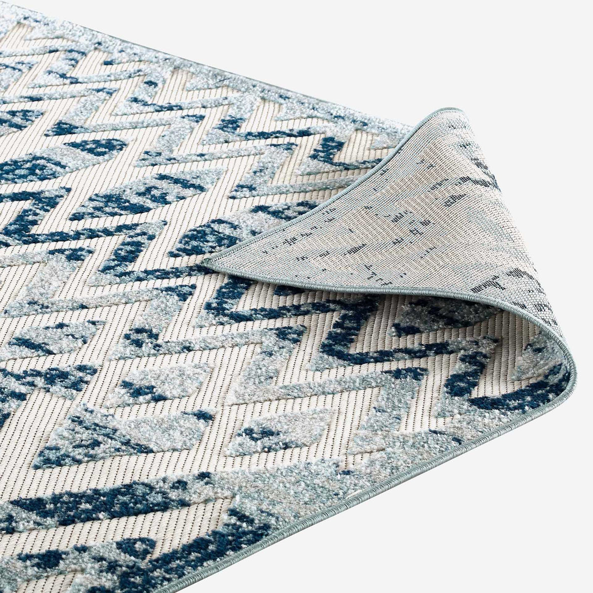 Woven backing and pale blue binding finish the flexible patterned rug