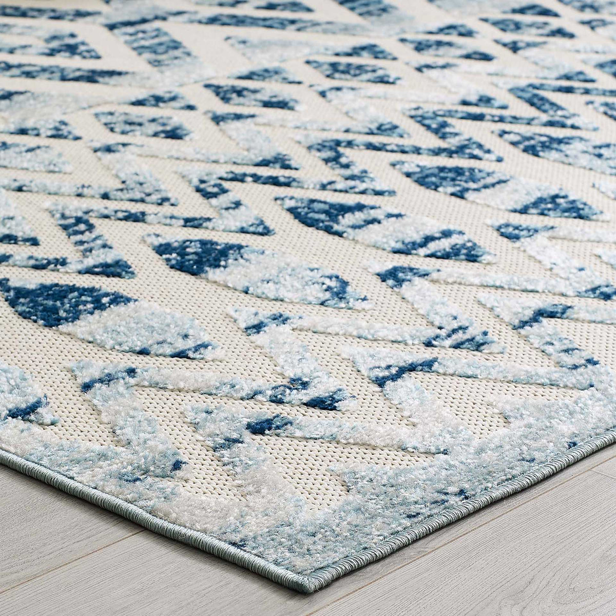 An ivory ground and softly raised blue motifs bring texture to the rug's bound edge