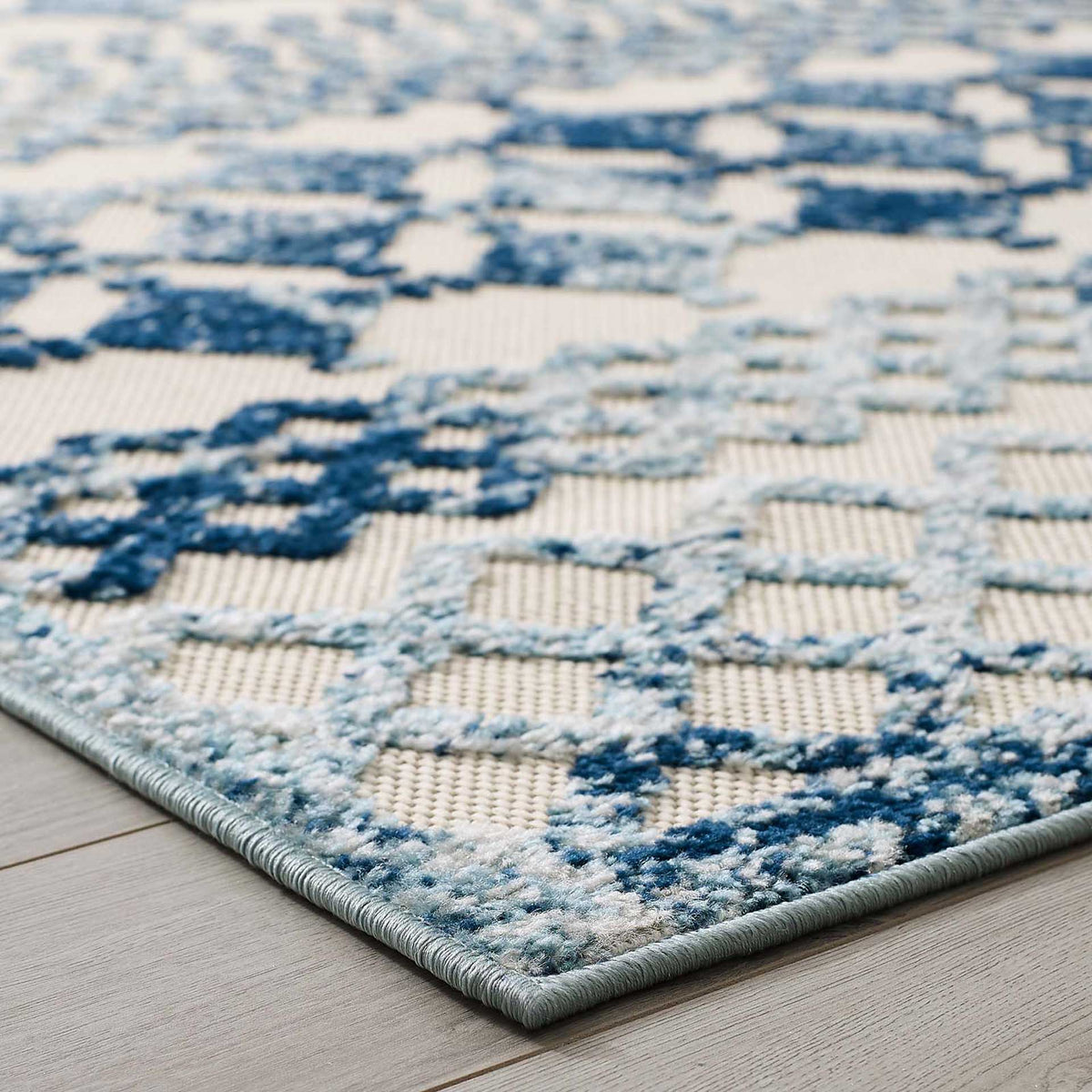 Raised blue motifs and a tailored edge lend tactile appeal to the ivory rug