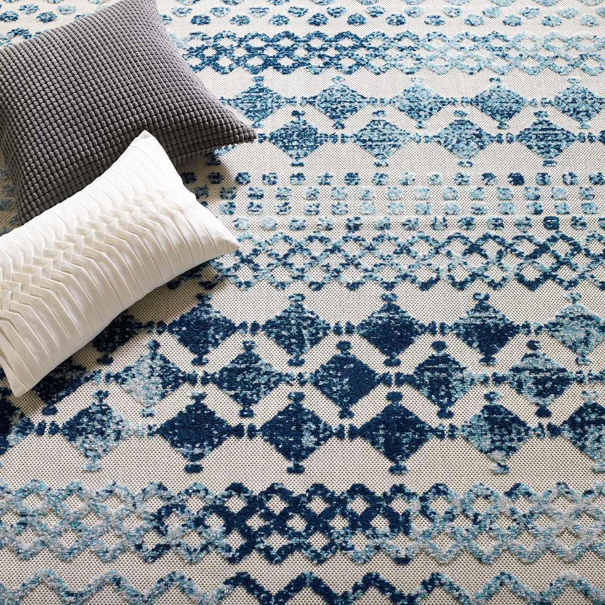 Bold navy diamonds and soft blue lattice bands add texture around floor cushions
