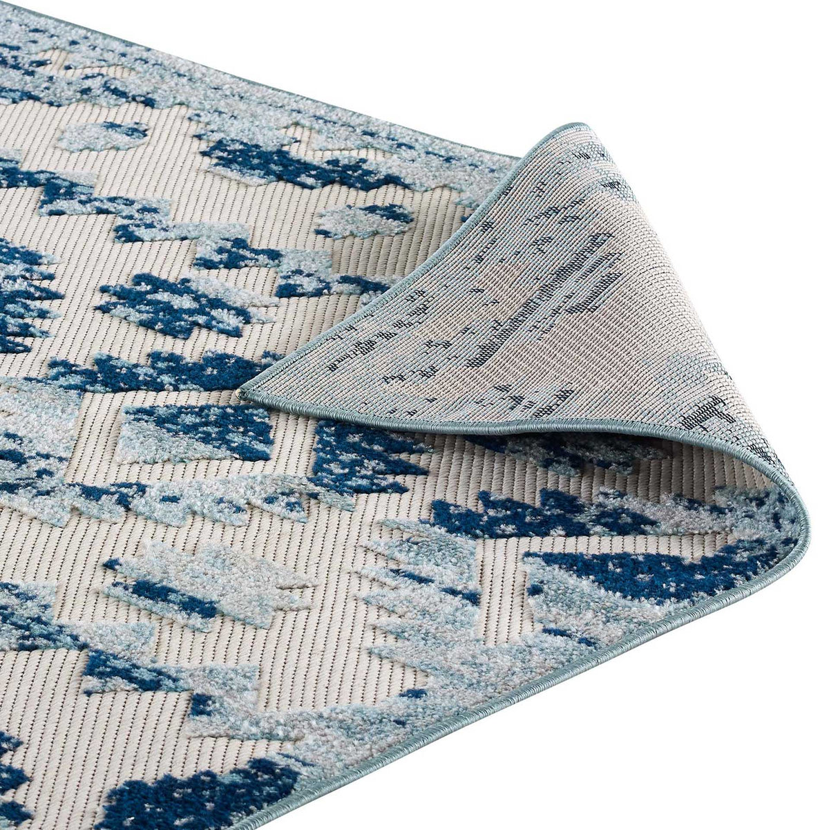 A flexible corner pairs woven backing with the rug's blue geometric face and bound trim