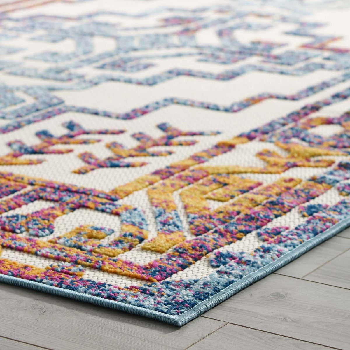 Raised blue, gold, and magenta threads enliven the rug's patterned edge