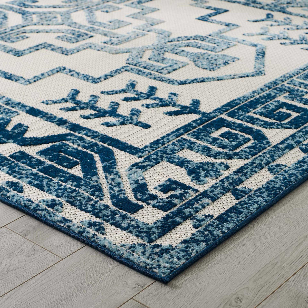 Deep blue borders and pale raised motifs add dimension to the ivory rug
