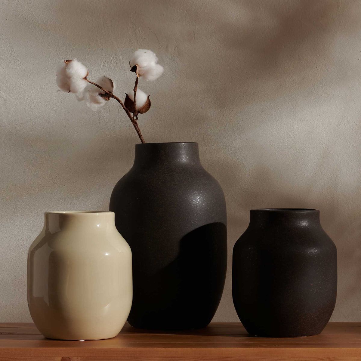 Charcoal and beige ceramic vases bring sculptural contrast to a console with a cotton stem display