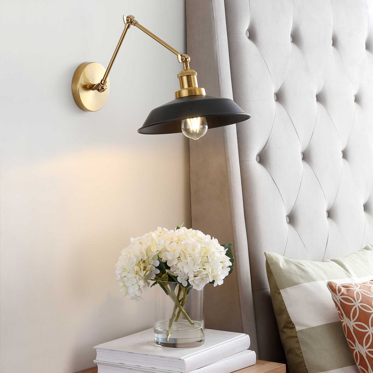 Warm light from the exposed bulb illuminates the bedside beneath a black dome shade.