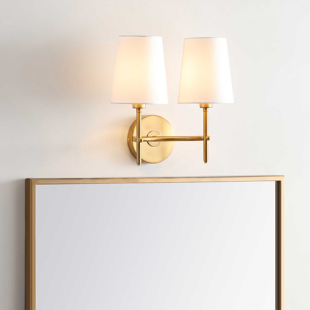 Two softly glowing shades add warm light to the brass-finished wall sconce.
