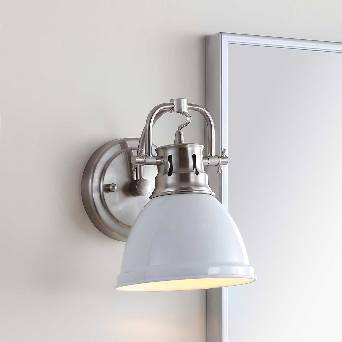 White and brushed nickel sconce illuminates the wall with a soft downward glow