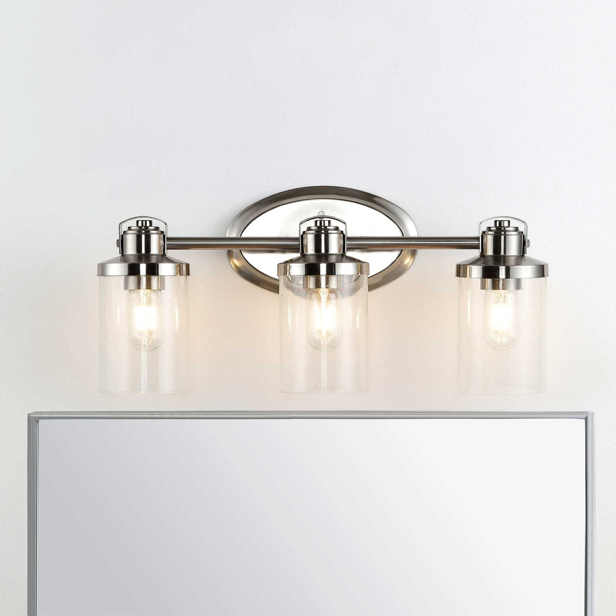 Three glowing glass shades brighten the space above a mirror with warm, inviting light