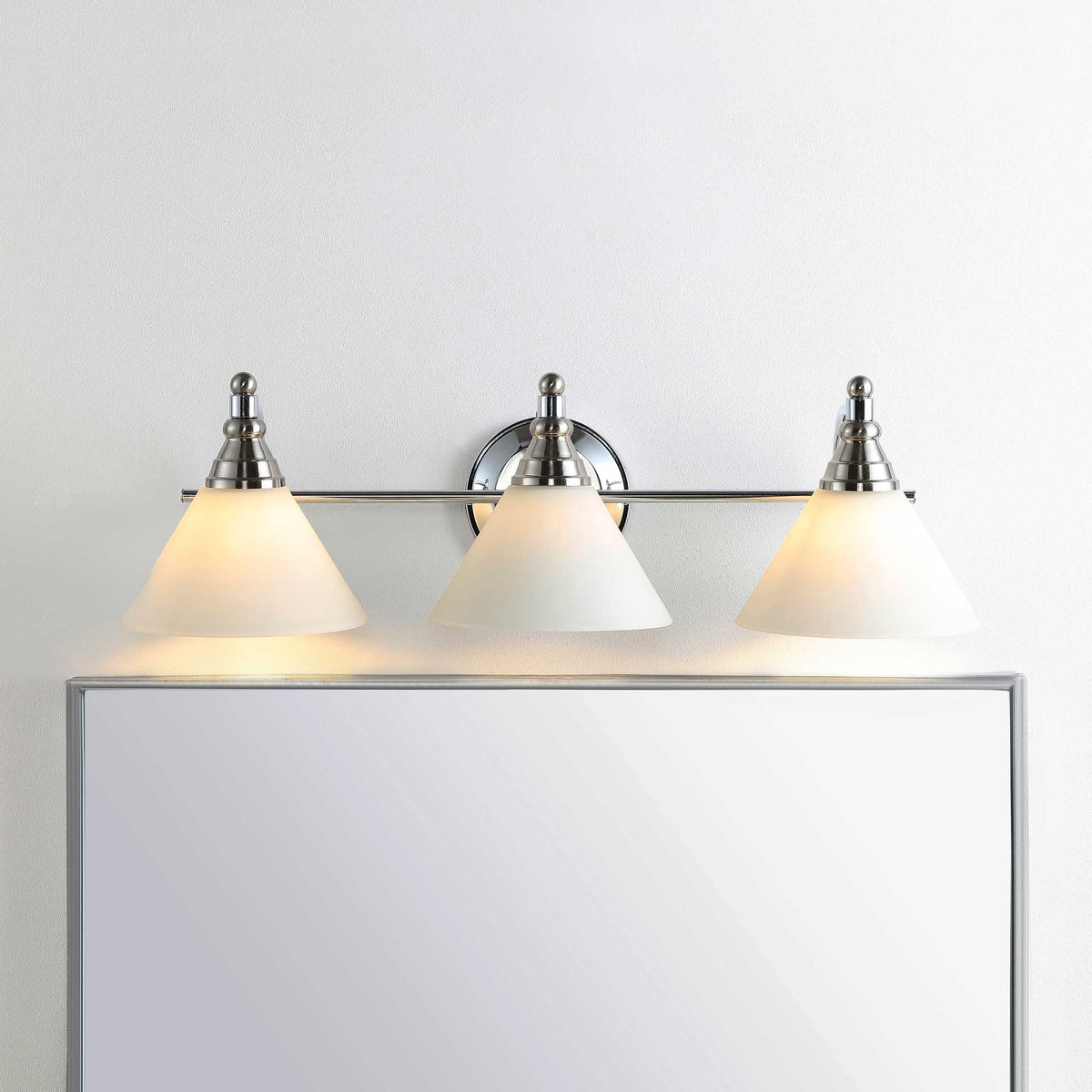 A trio of glowing glass shades adds warm, even illumination above a mirror