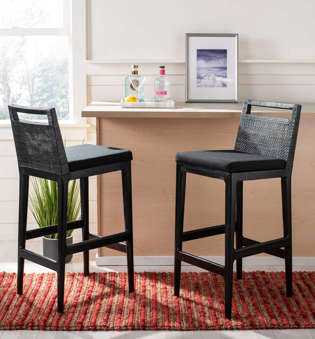 Woven-back bar stools with black cushions bring relaxed seating to a light wood counter.