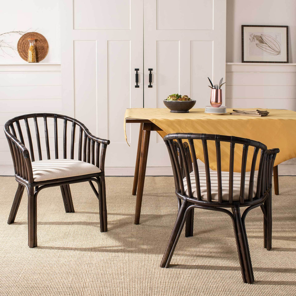 Two dark brown rattan armchairs with white cushions lend airy curves to a warm dining space.