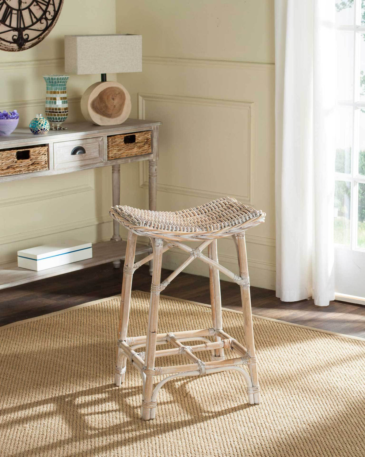 Backless woven rattan stool adds natural texture and relaxed coastal character beside a console table