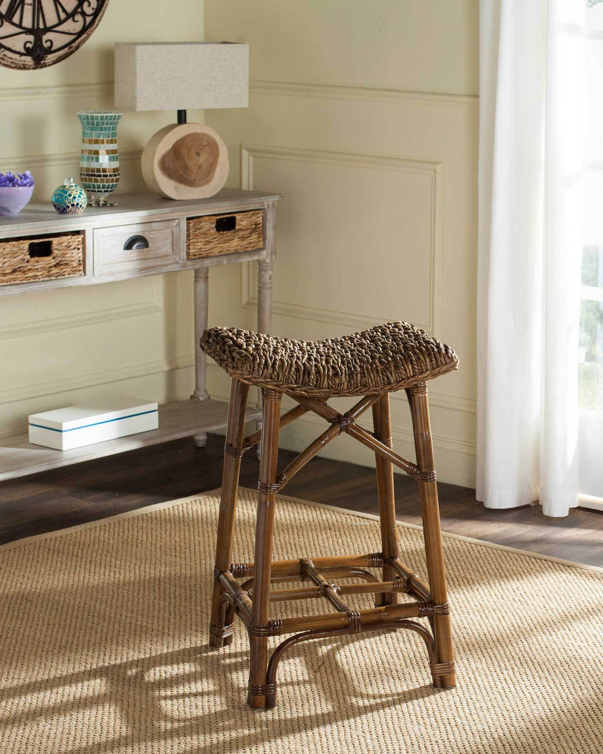 A brown rattan bar stool adds a textured woven seat and relaxed coastal warmth to the living room