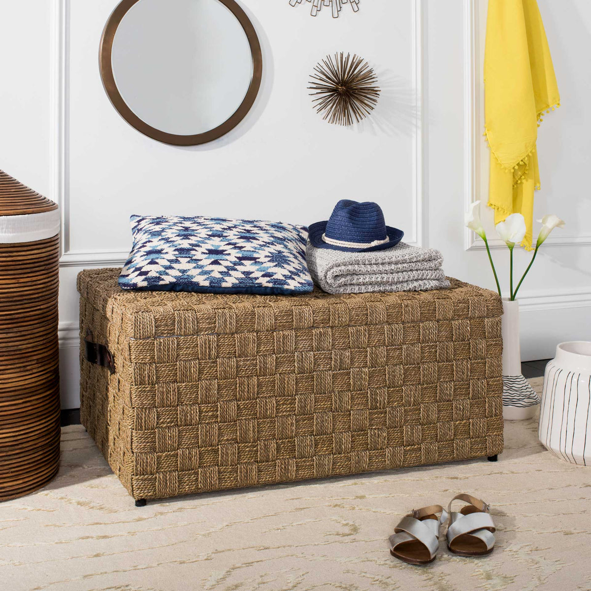 Natural woven trunk offers a textured surface for folded blankets and storage beneath the lid