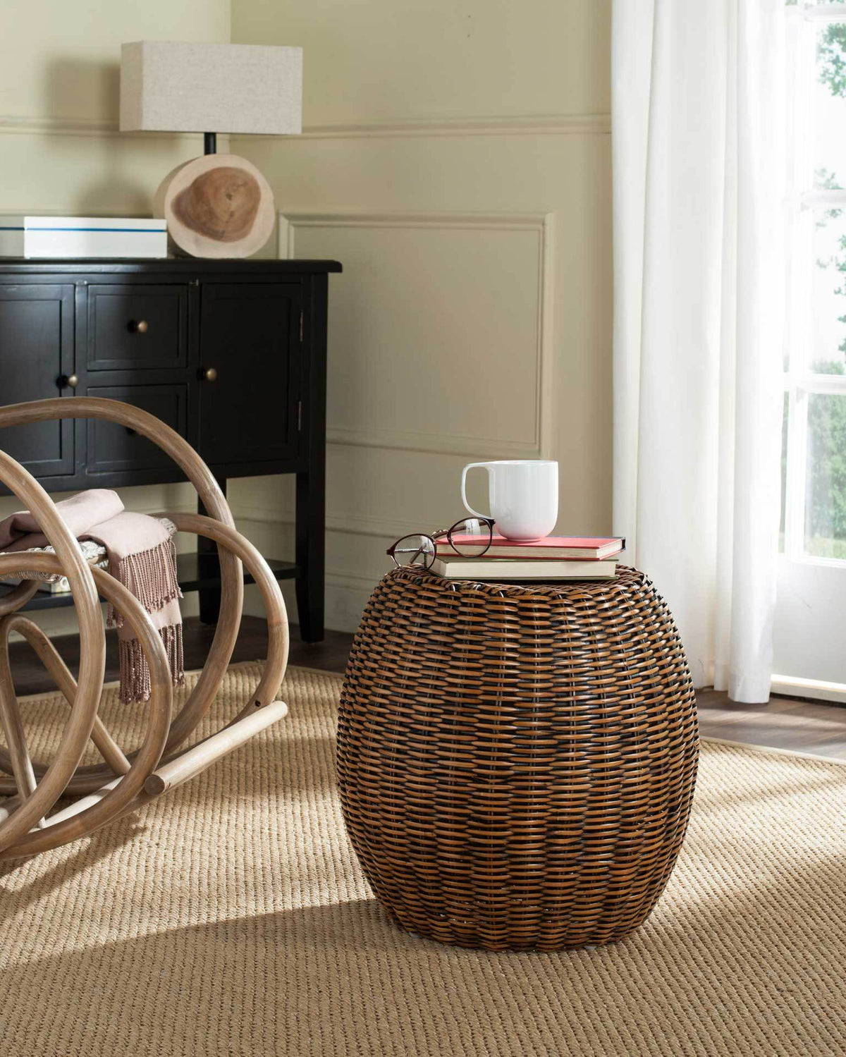 Warm brown rattan end table with a rounded silhouette and a surface for books and a cup