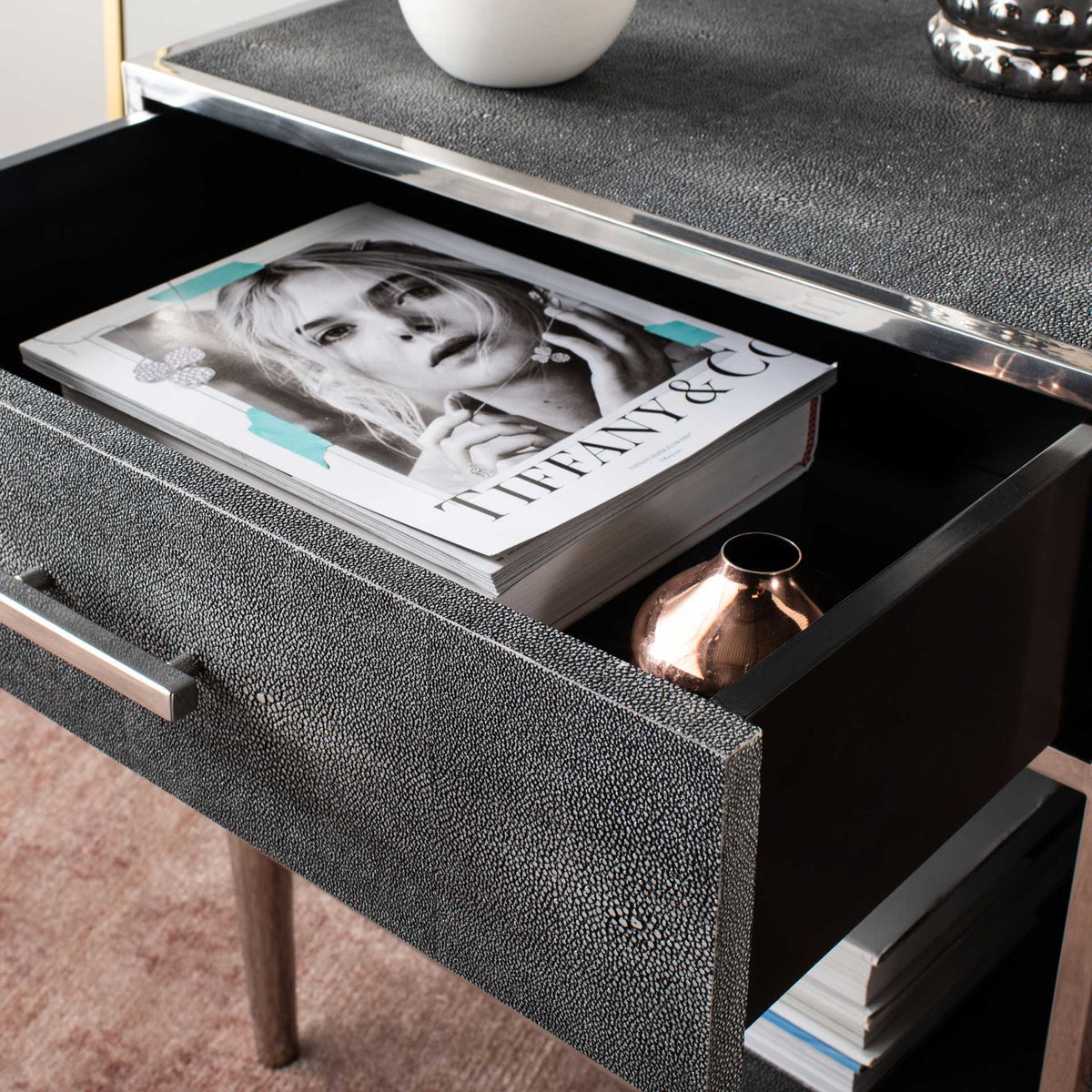 An open drawer holds a book and small accents above the nightstand's lower shelf
