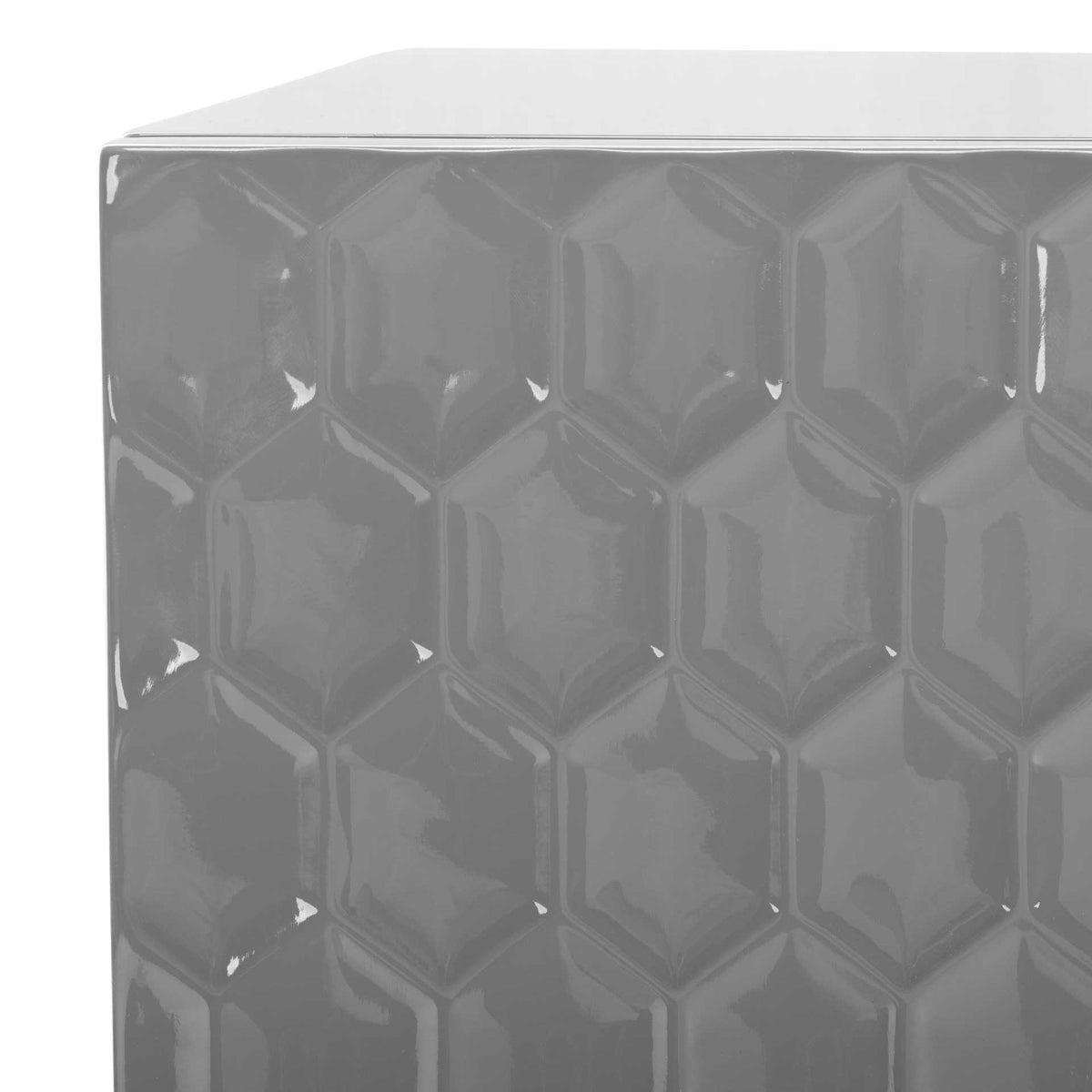 Raised hexagonal detailing lends depth and shine to the gray drawer front beneath a smooth tabletop.