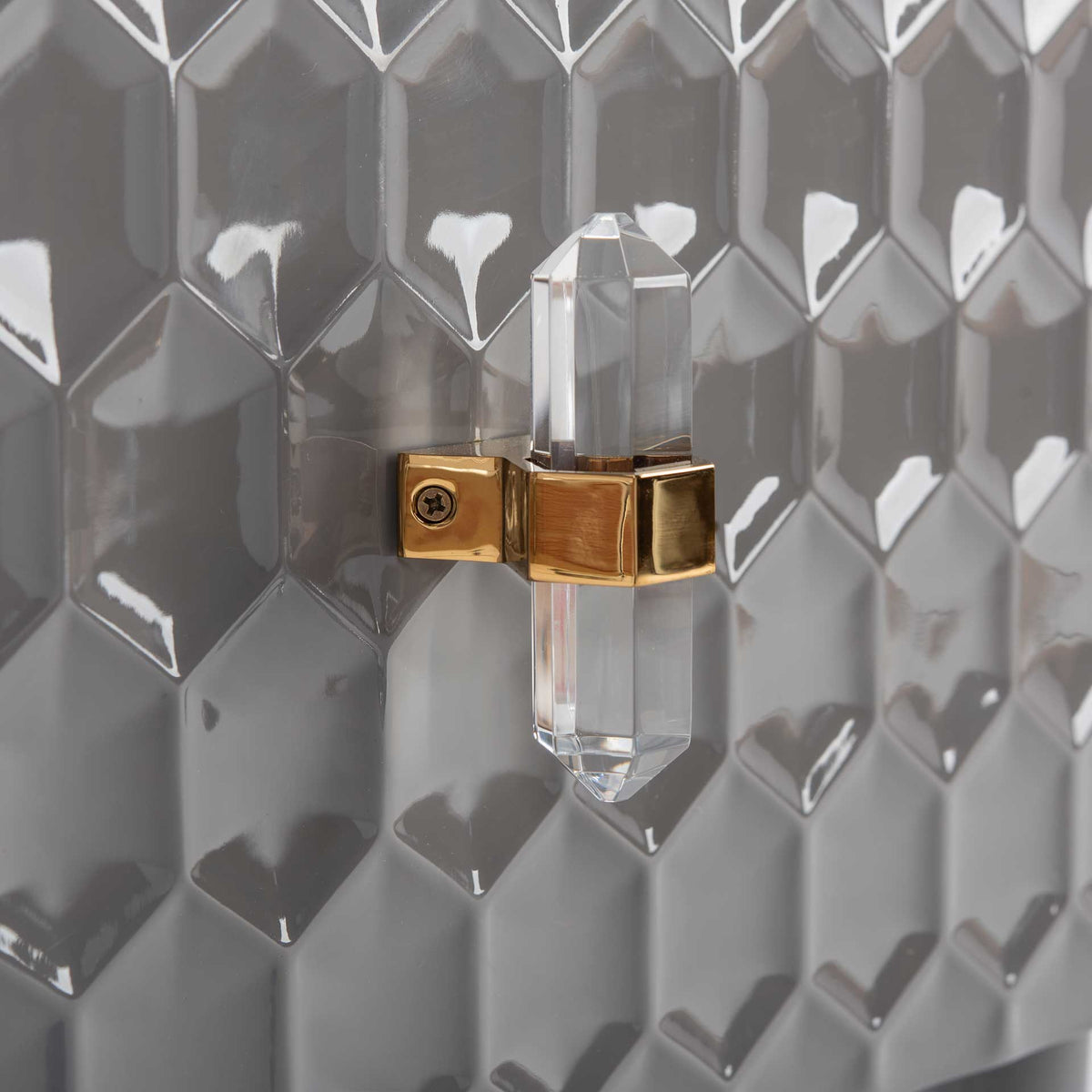 A clear faceted drawer pull with a gold-tone mount accents the glossy gray honeycomb design.