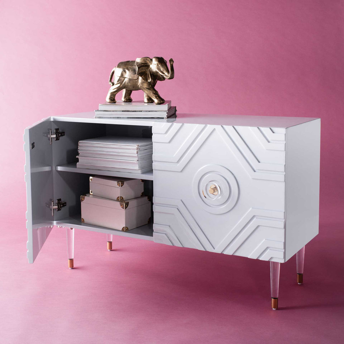 An open cabinet door reveals storage for stacks of reading material and decorative boxes