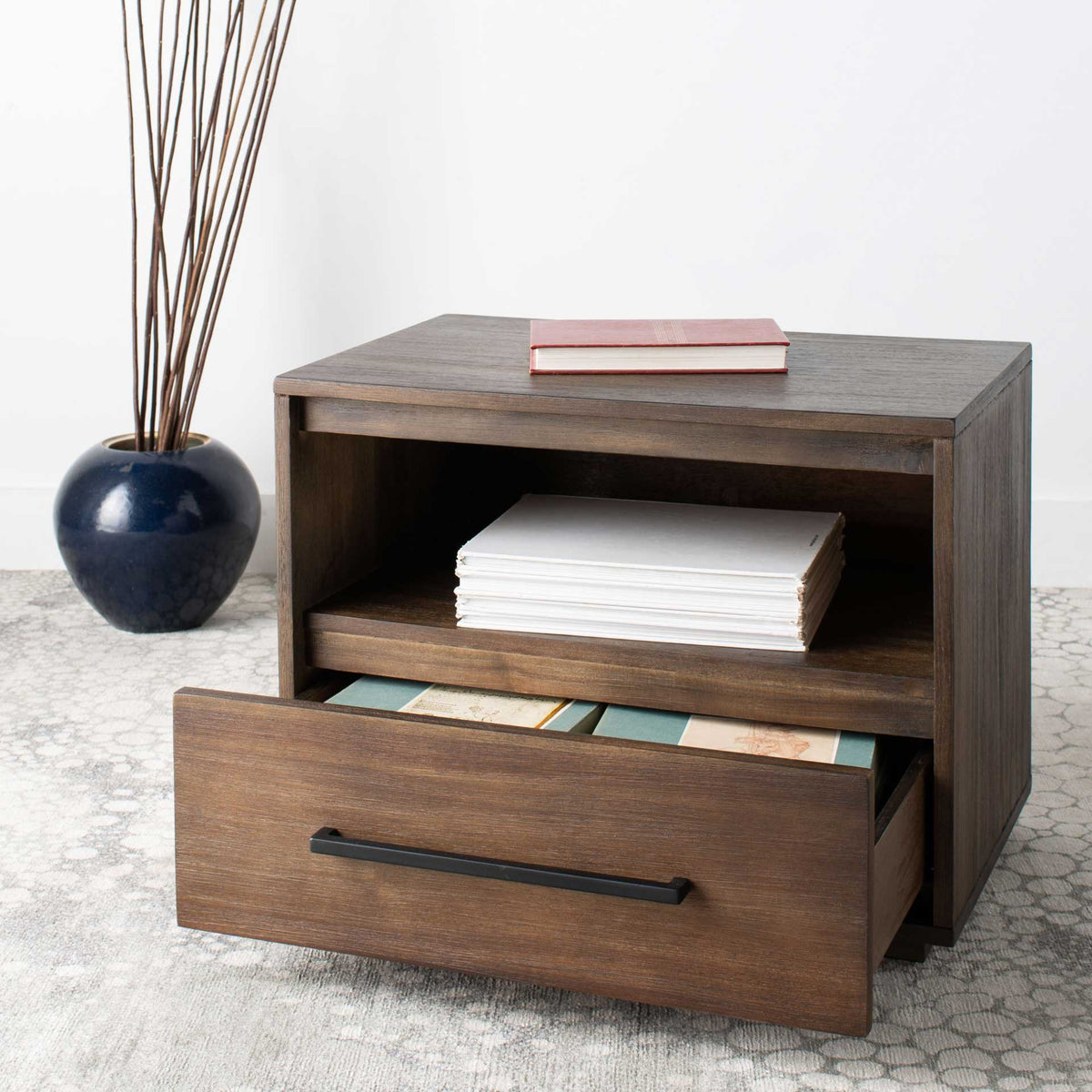 A roomy pull-out drawer holds books and magazines beneath a shelf of folded linens