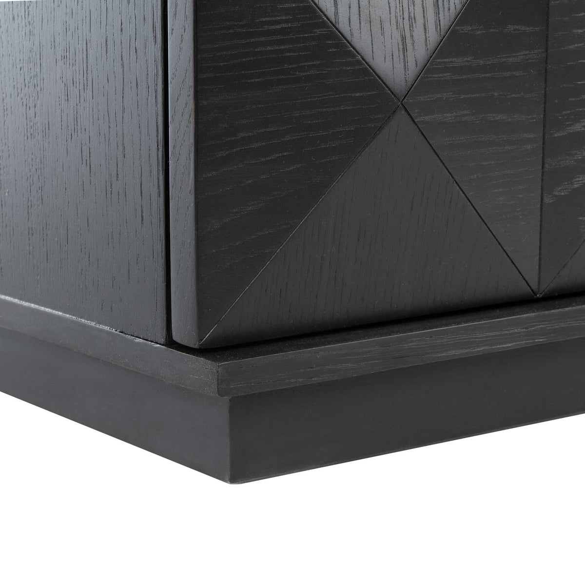 A low black plinth base supports the nightstand beneath its faceted drawer fronts