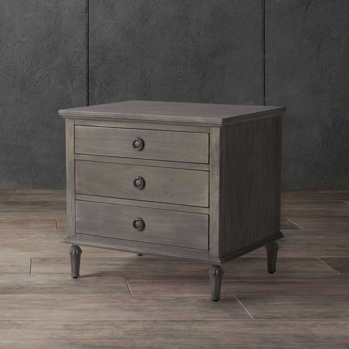 Light gray three-drawer nightstand pairs softly textured wood grain with elegant metal knobs.