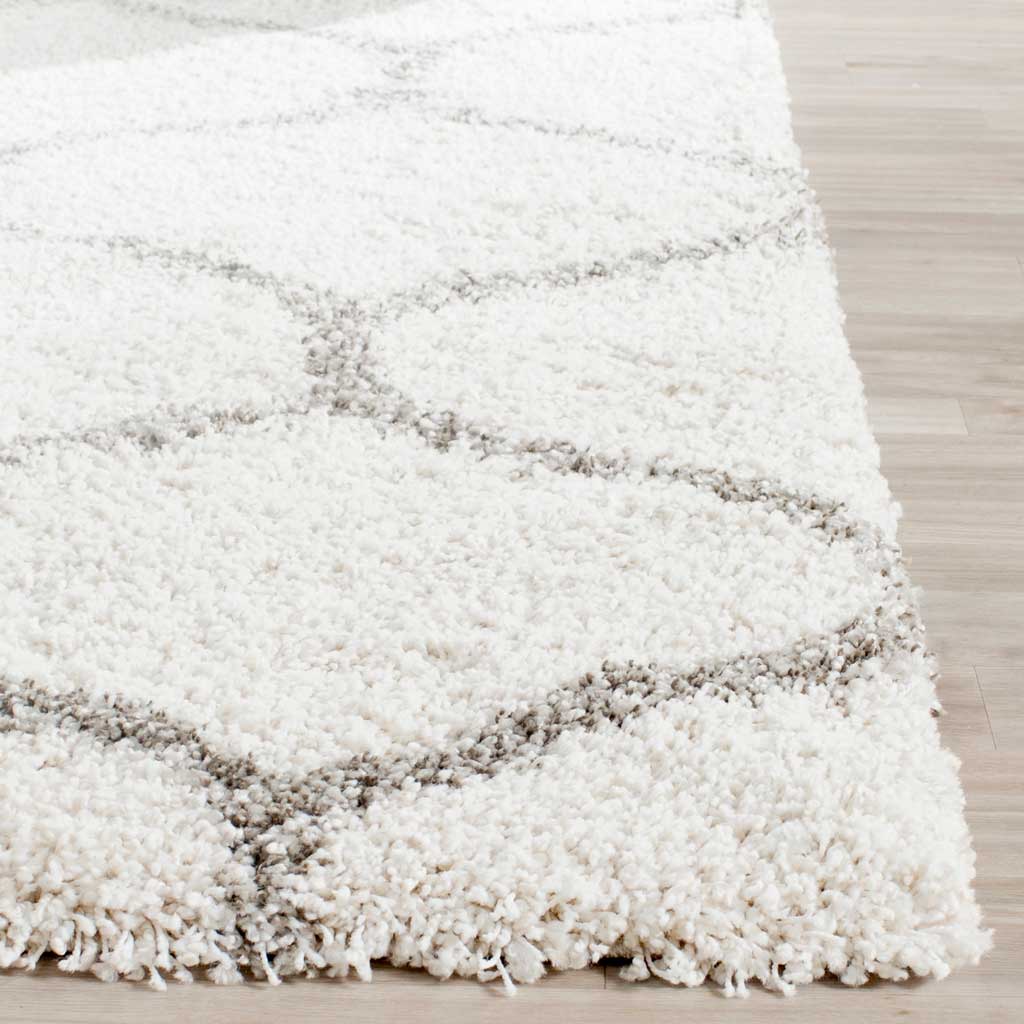 Long ivory fibers soften the gray curves along the rug's edge