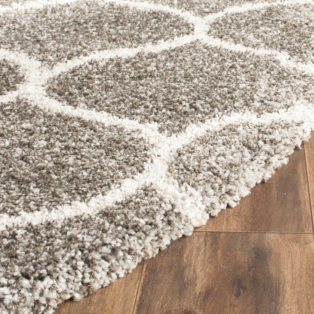 Gray shag fibers and ivory curving outlines add soft definition to the rug's edge