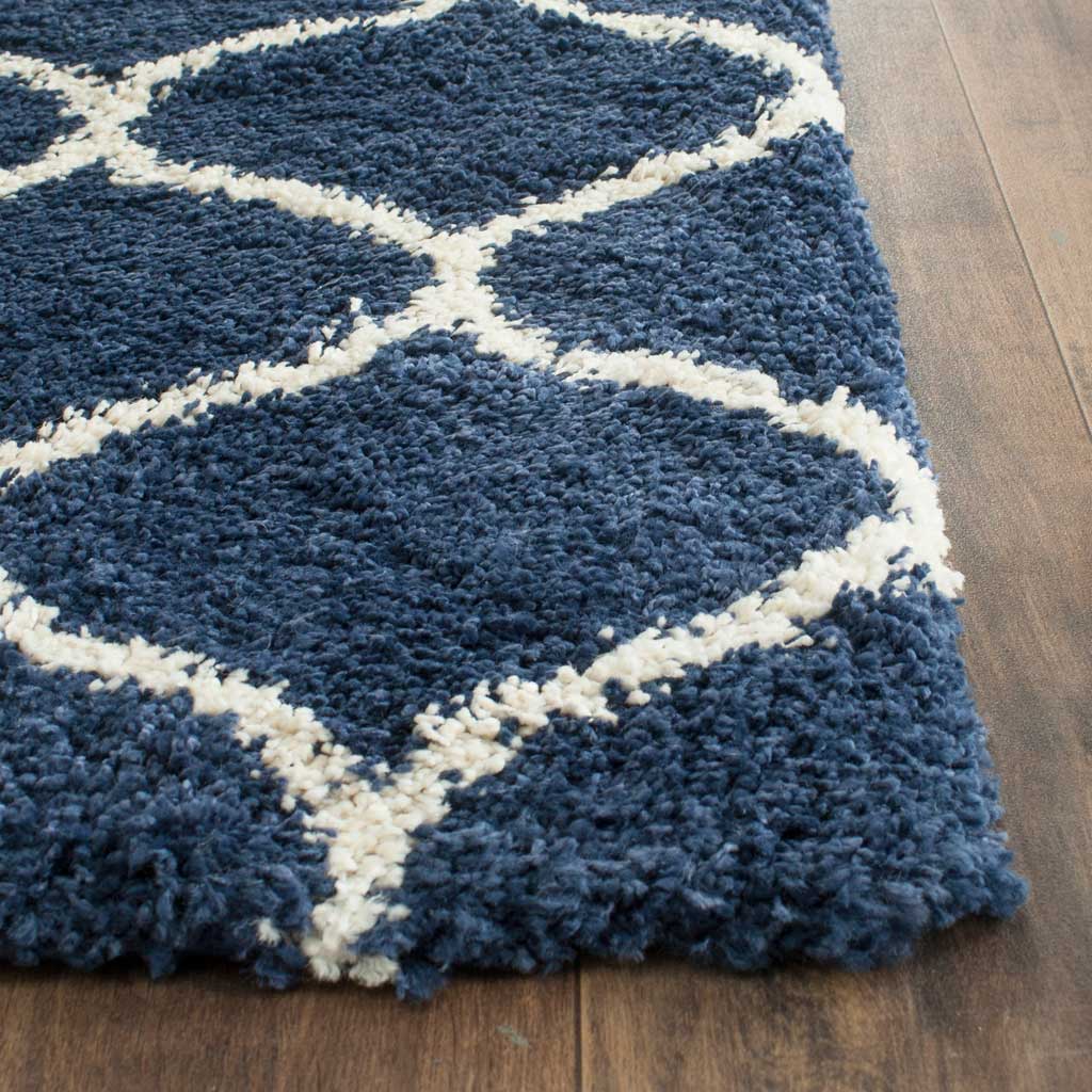 Dense navy fibers and ivory trellis lines meet at a plush, thick rug corner.