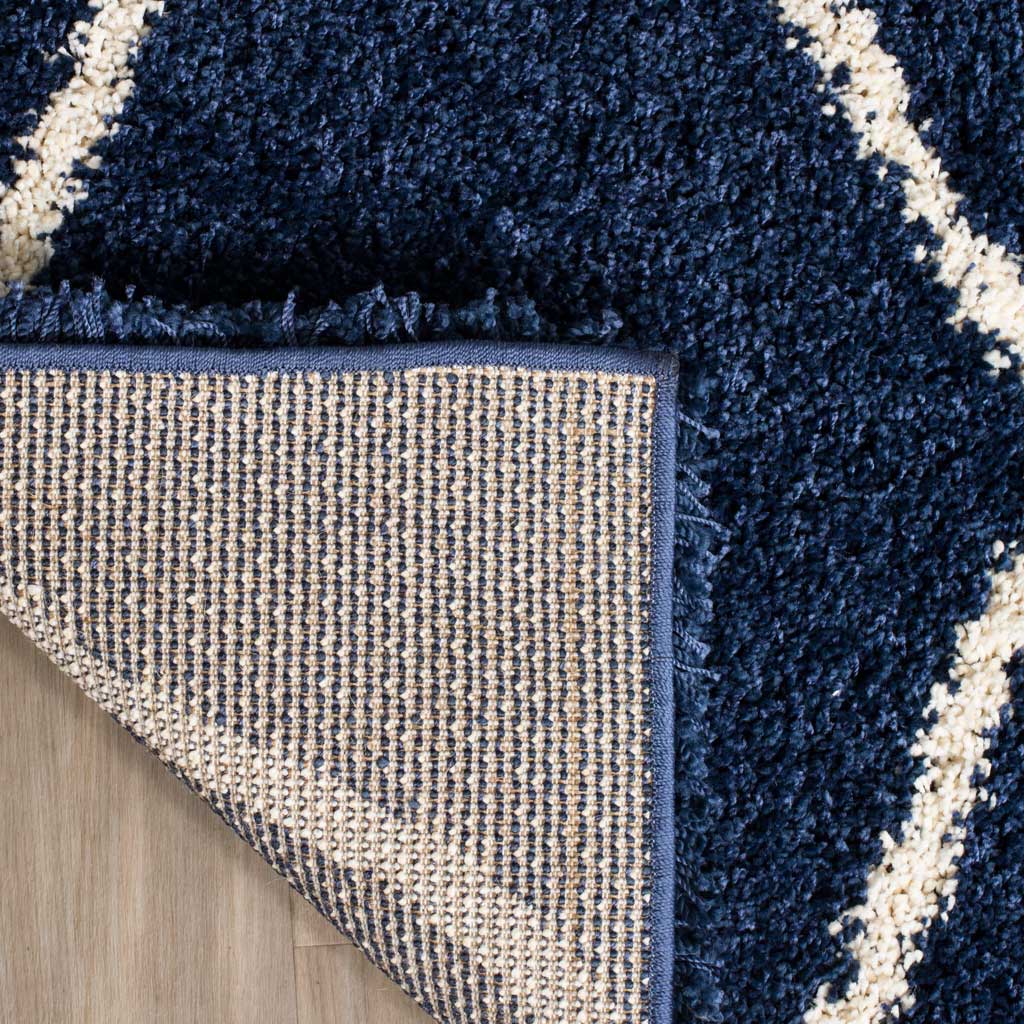 Woven underside and navy binding support the plush patterned rug