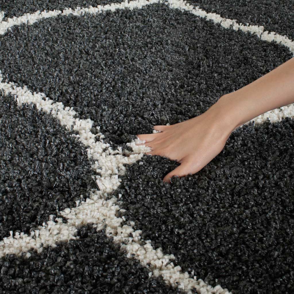 A hand presses into the deep charcoal pile beside an ivory contour