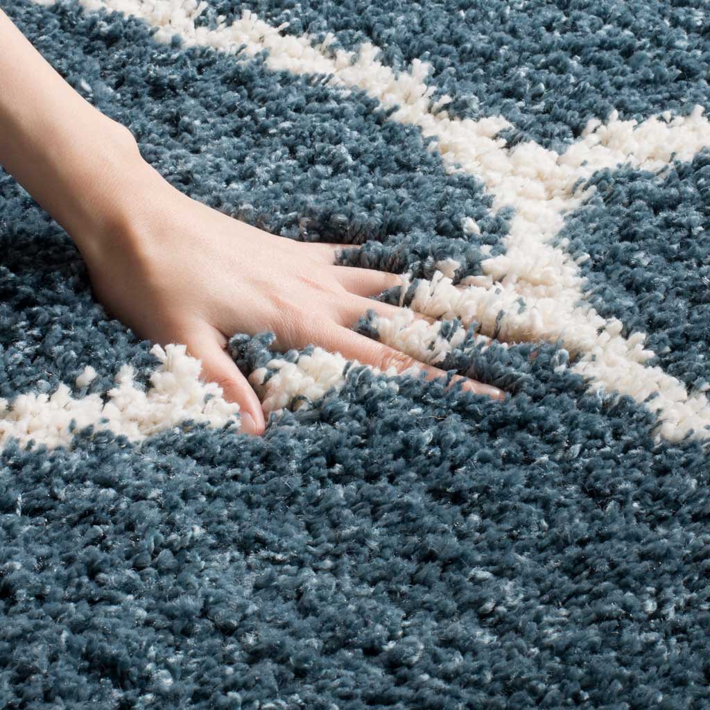 A hand sinks into slate blue shag beside the raised ivory lattice
