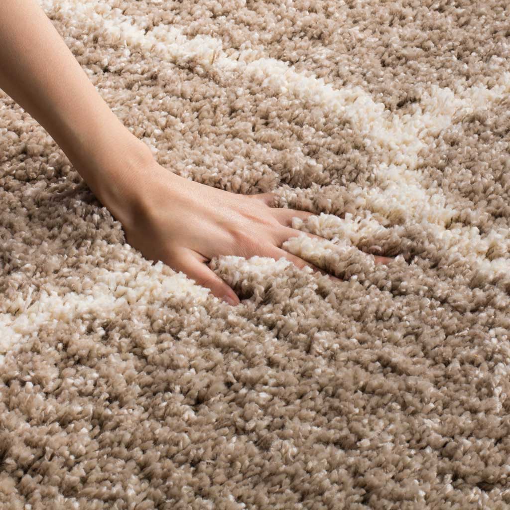 A hand nestles into thick beige shag beside an ivory line