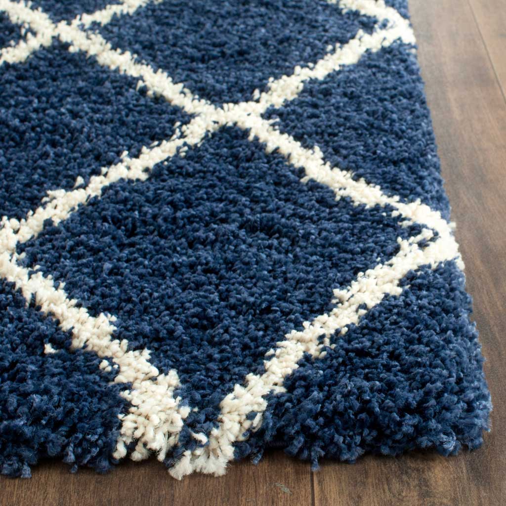 Ivory lattice lines cut through dense navy fibers along the plush rug corner.