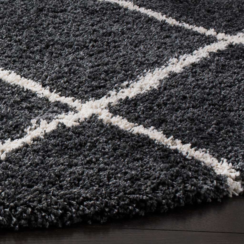 Dense dark gray shag frames ivory lattice lines at the rug's cushioned edge