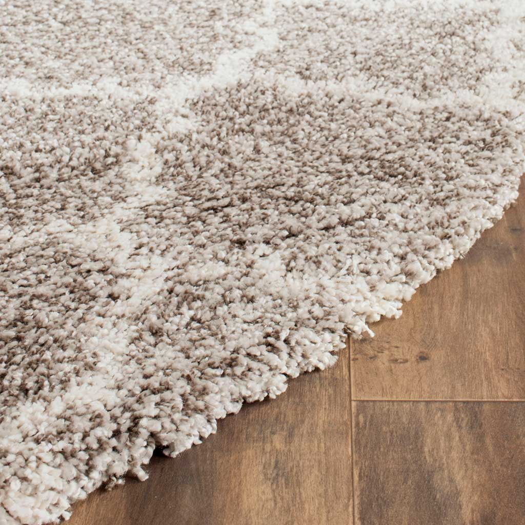 Ivory outlines weave through mottled gray shag beside the rug's plush edge