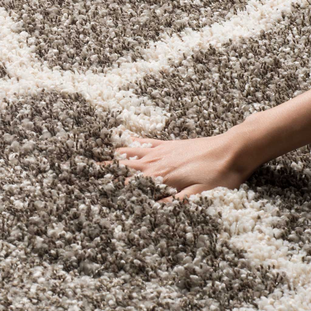 A hand sinks into the dense gray shag between ivory lines
