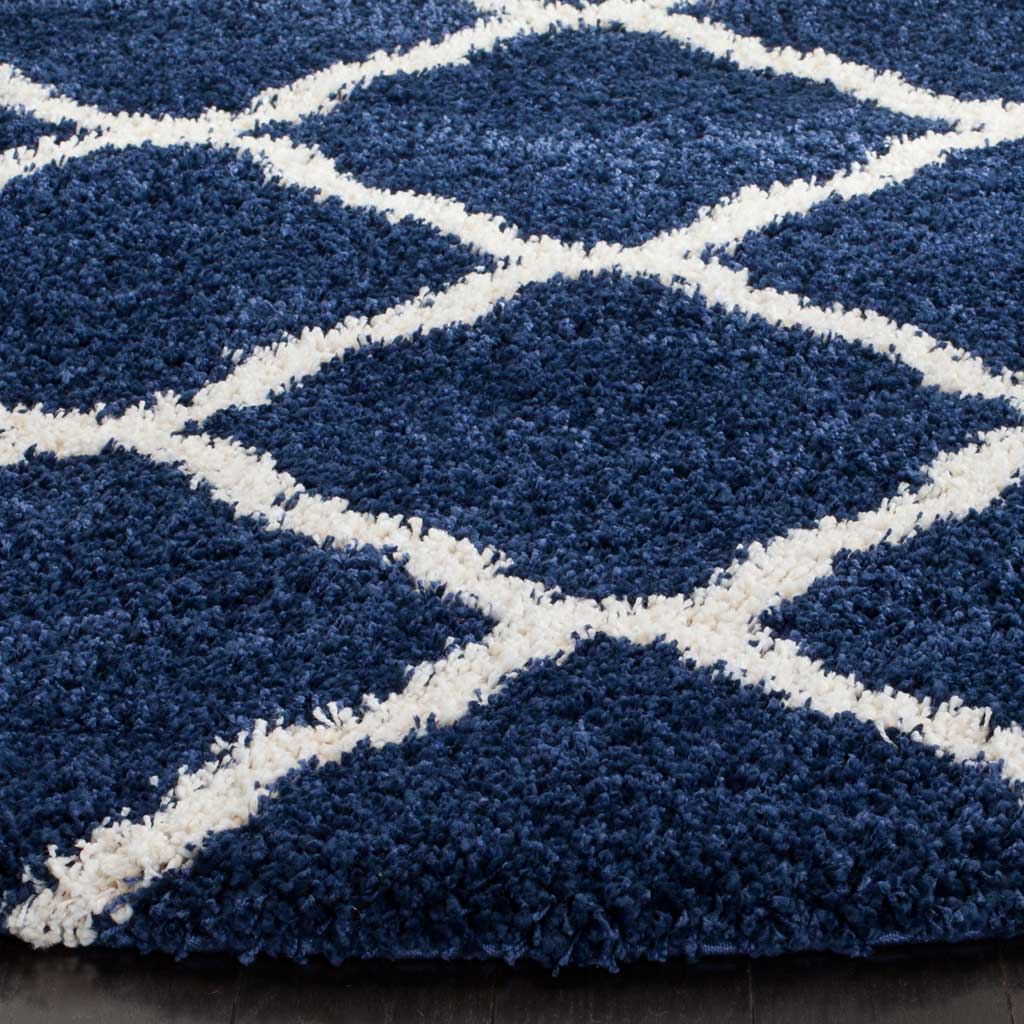 Deep navy fibers frame raised ivory trellis lines along the rug's plush edge