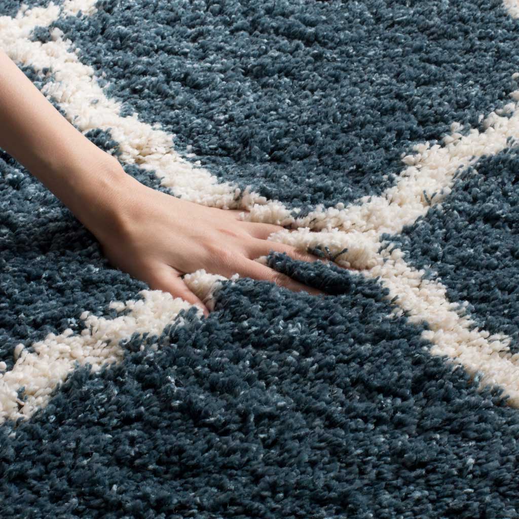 A hand nestles into the plush blue pile beside ivory detailing