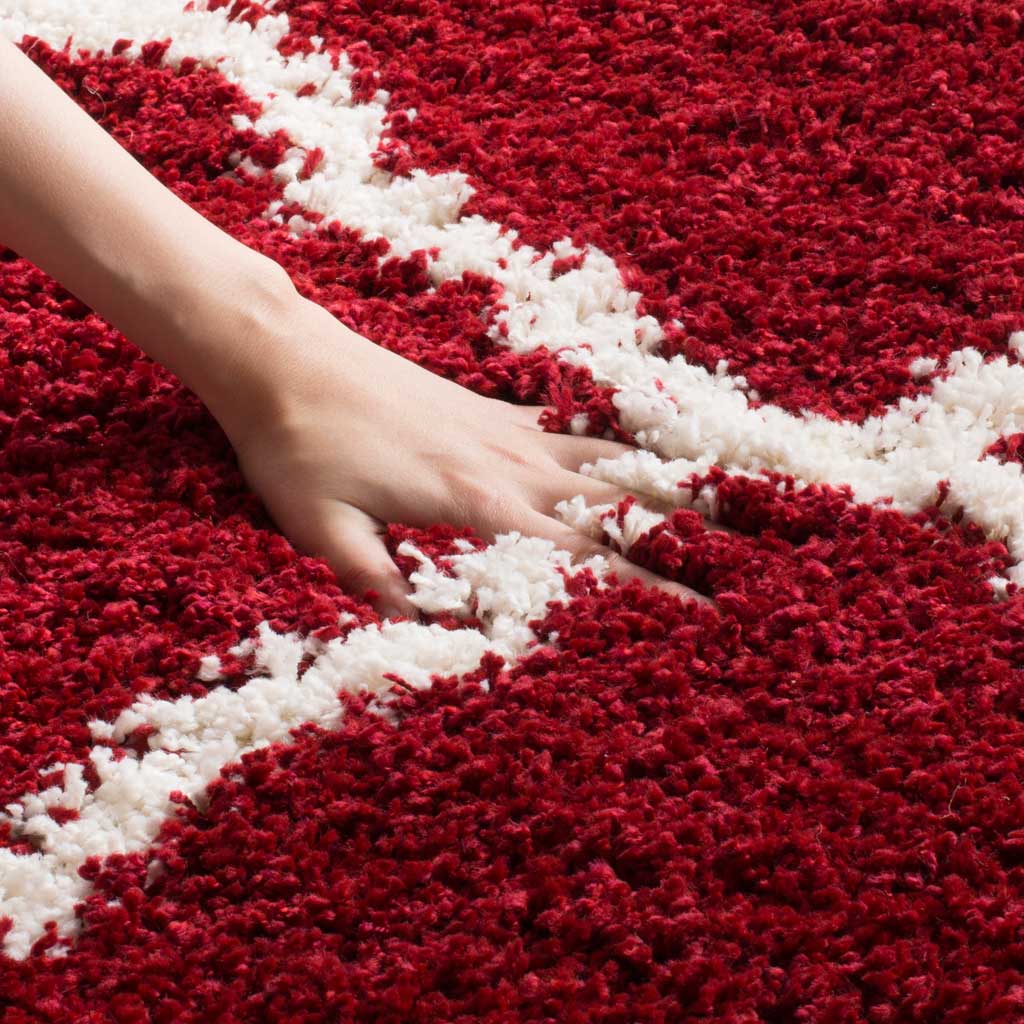 A hand sinks into the deep red shag beside an ivory line