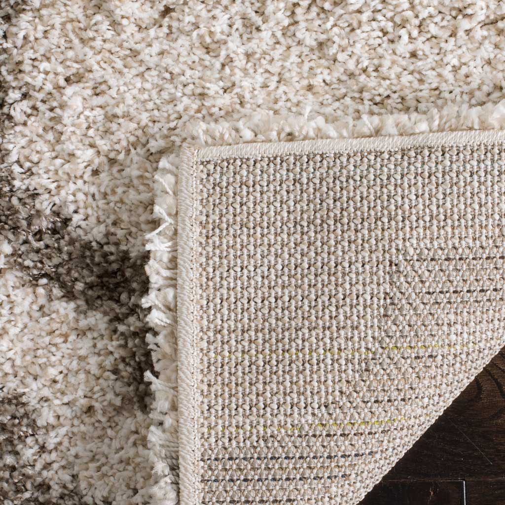 Woven backing lies beneath the ivory pile and gray design