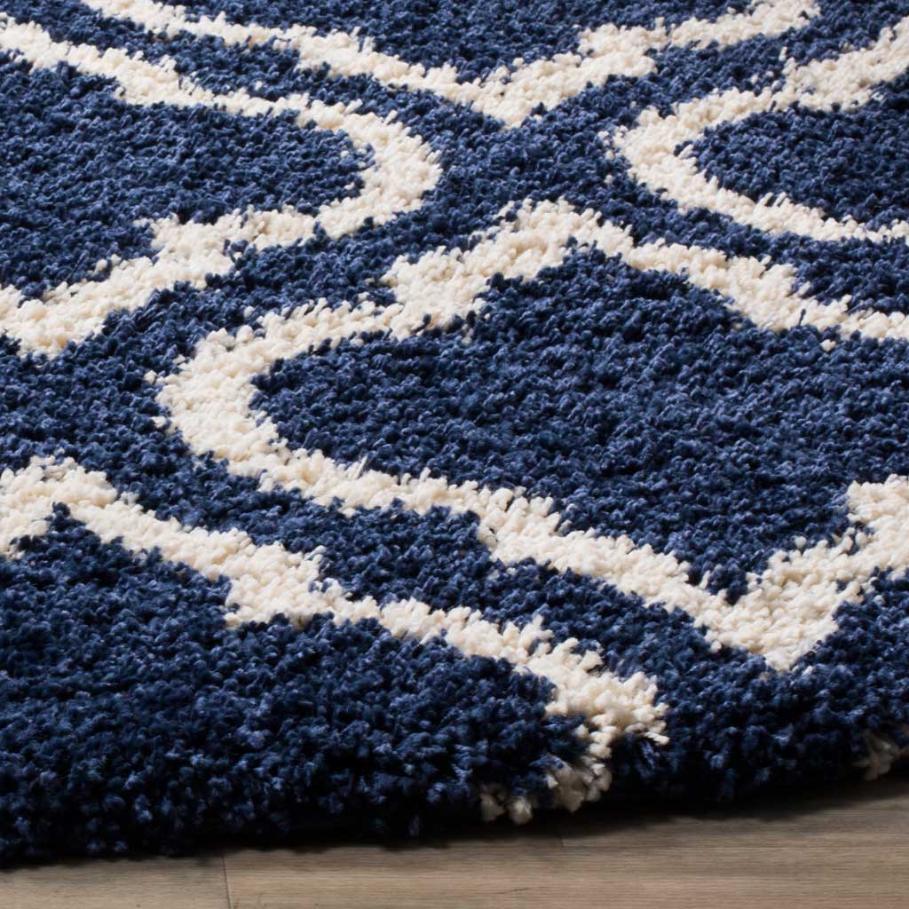 Thick navy pile sets off sweeping ivory ogee lines along the soft rug edge