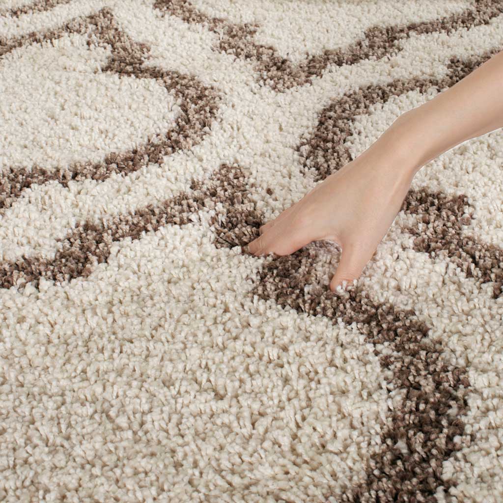 A hand settles into the thick ivory pile between beige lines