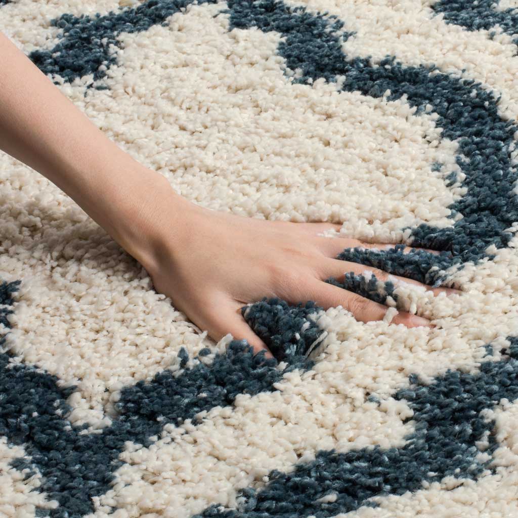 A hand presses into the ivory pile beside a steel blue motif