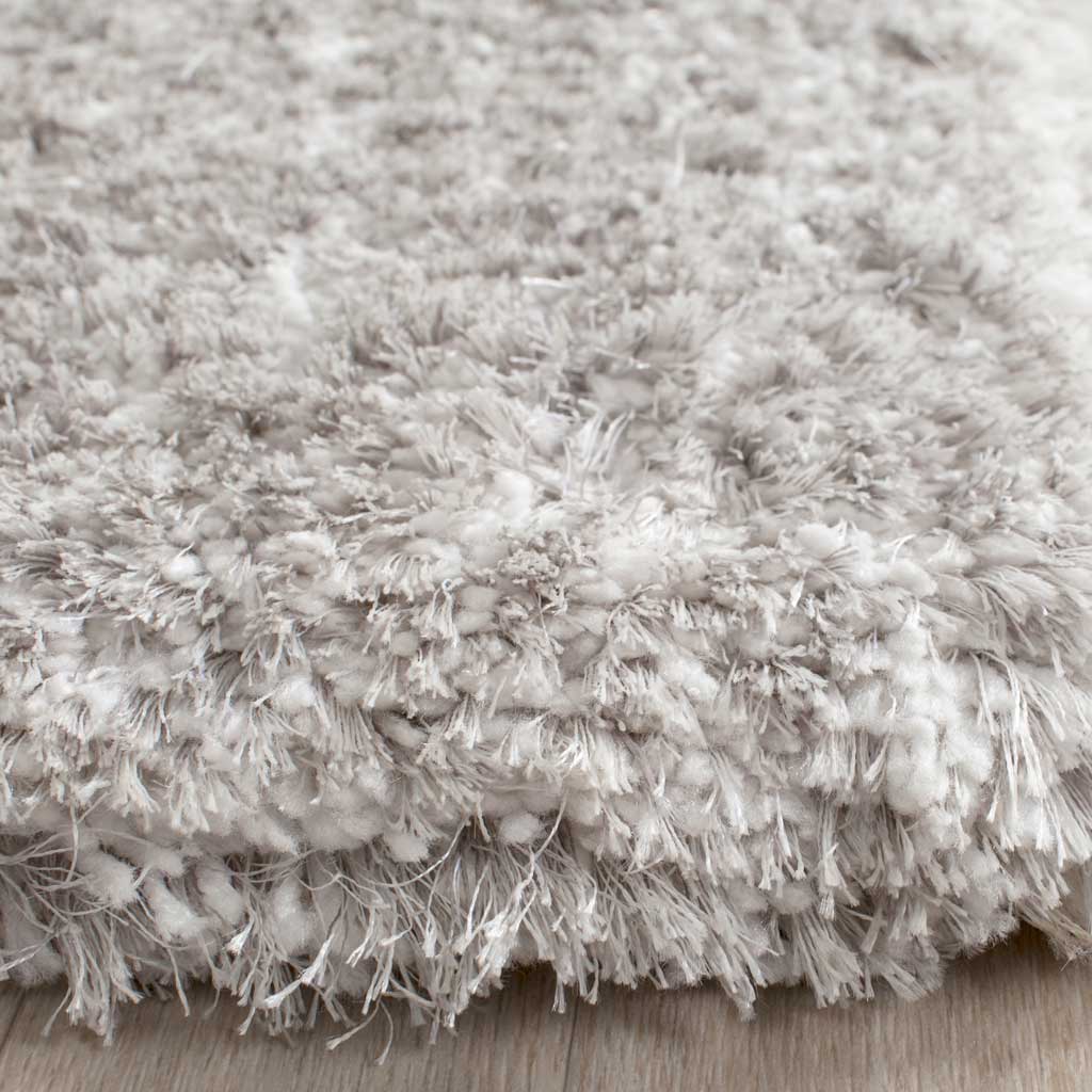 Thick light gray shag reveals airy fibers and an invitingly plush edge