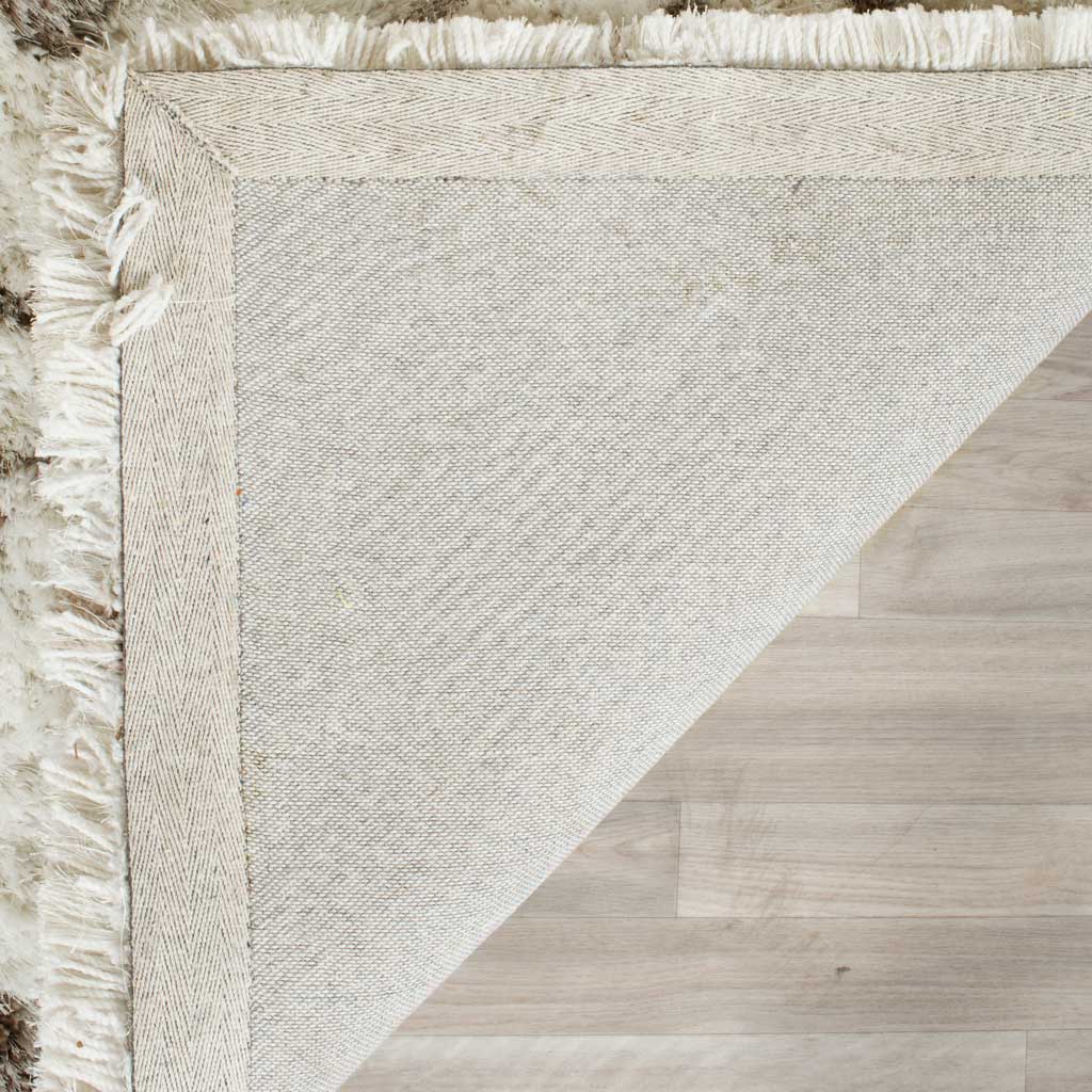 A woven backing and neatly finished border support the ivory and gray shag rug