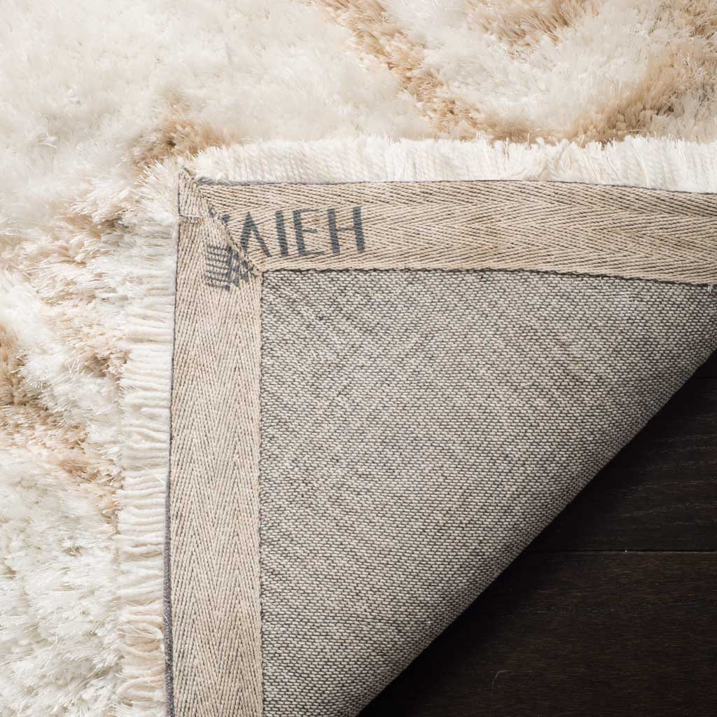 A woven underside and stitched border anchor the plush ivory and beige shag rug