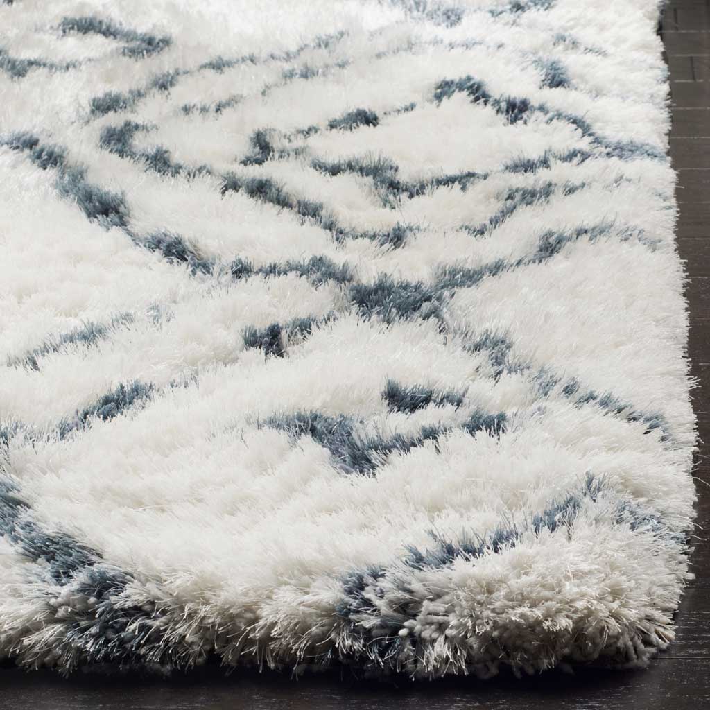 Lofty ivory pile and blue geometric lines meet along a thick, soft rug edge