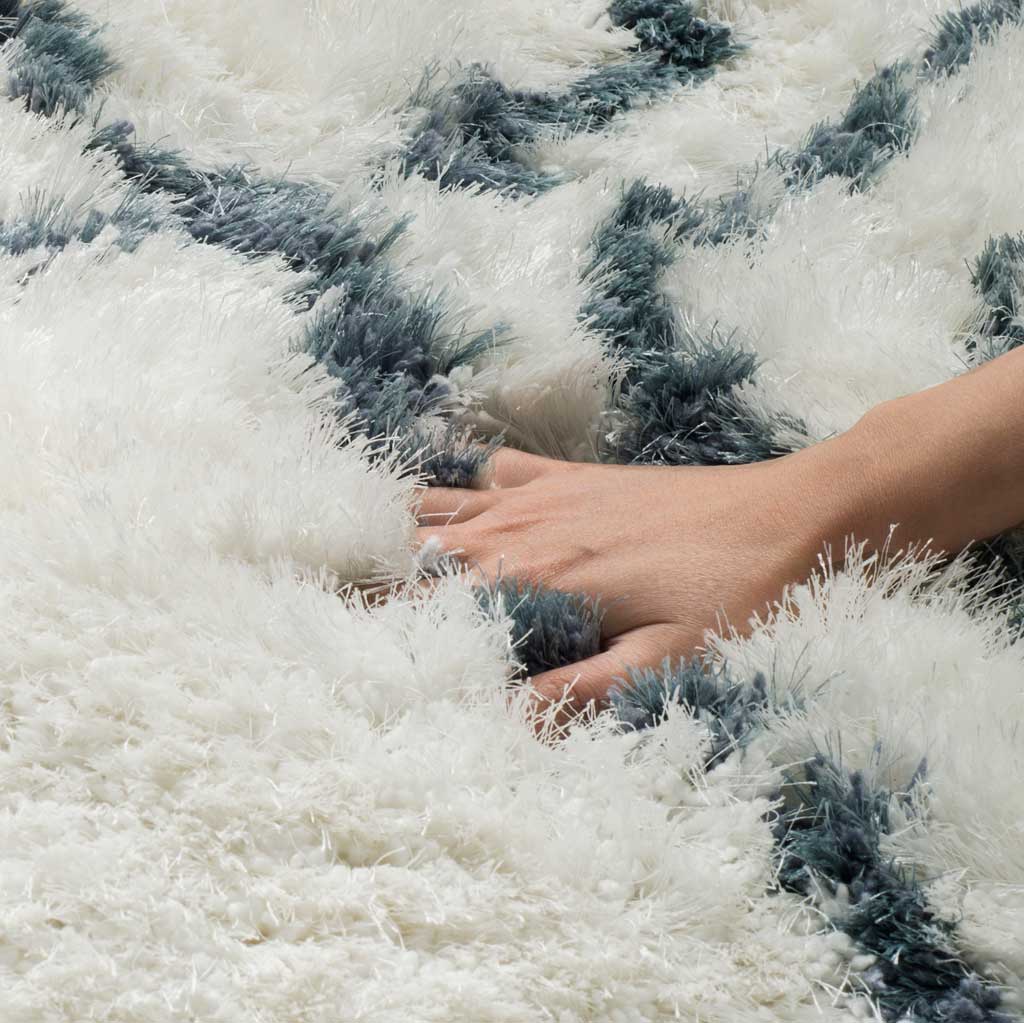 Long ivory shag fibers and deep blue accents create a richly textured, cushioned surface